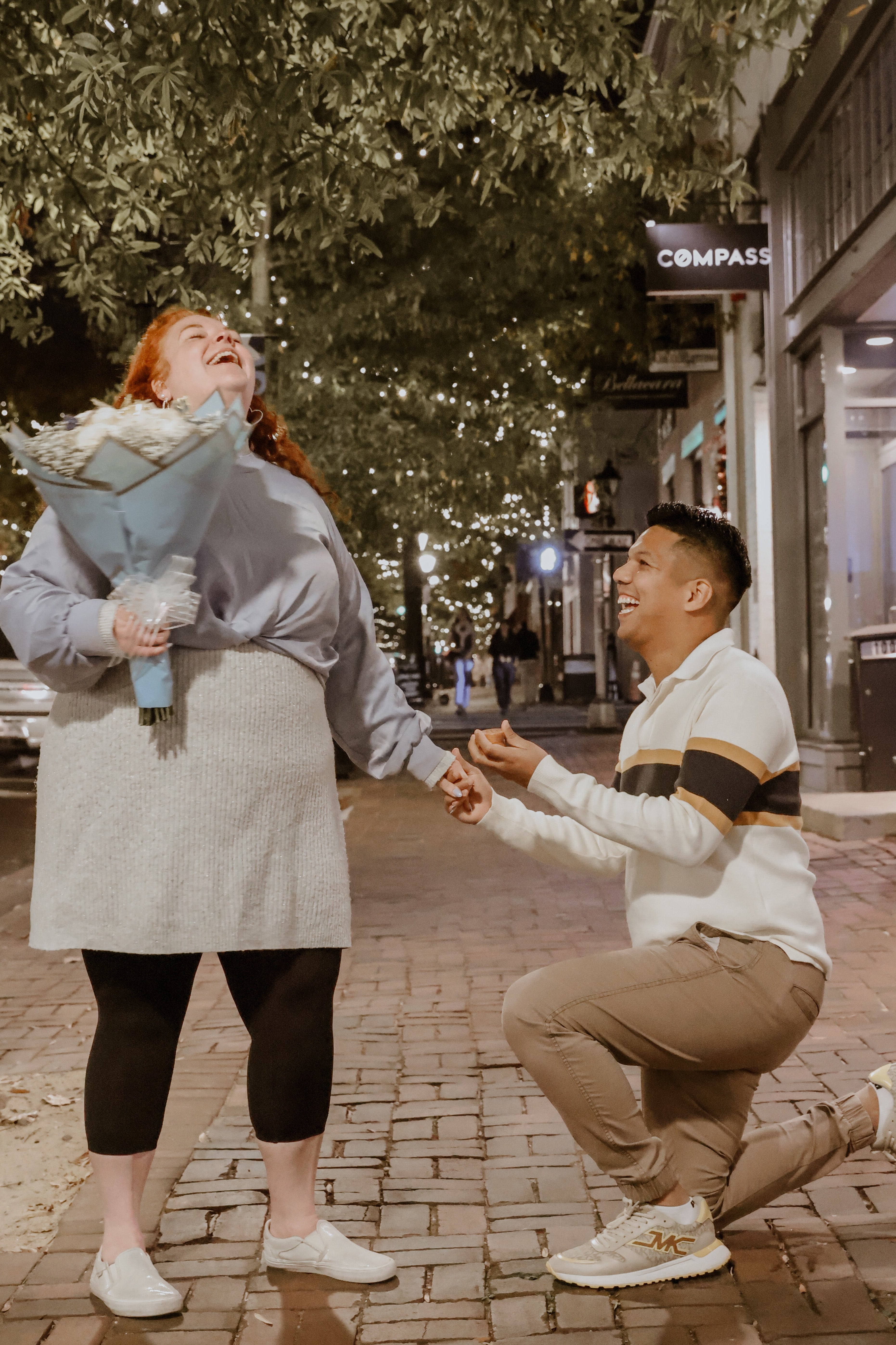 Man proposing to a woman on a city street at night.